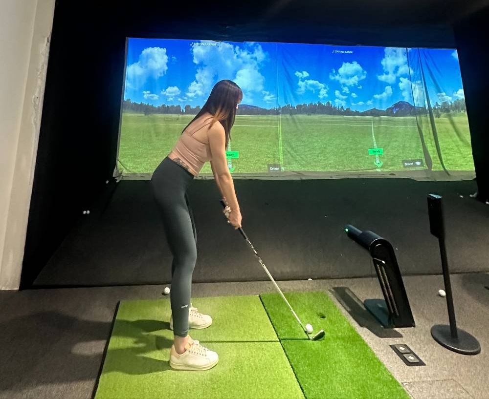 Practicing golf swing at an indoor golf simulator.
