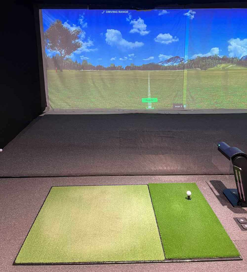 An indoor golf simulator setup designed to simulate a driving range or golf course experience indoors.