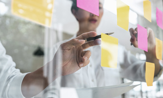 Creative services team using colourful sticky notes on a glass wall to brainstorm or map out a creative strategy.