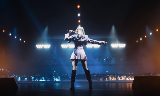 Pop music artist performing on a concert stage in front of an audience.